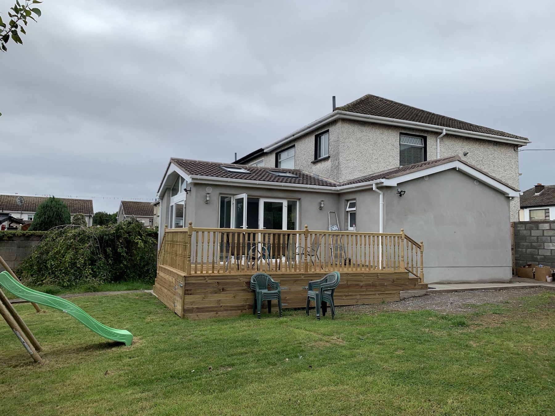 The rear of a house with a single-storey extension and a raised timber deck on the lawn